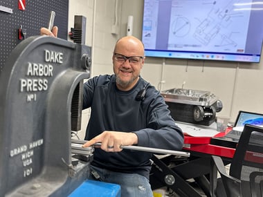 smiling-employee-using-drake-press-and-working-in-robotic-cart-assembly-area-808px