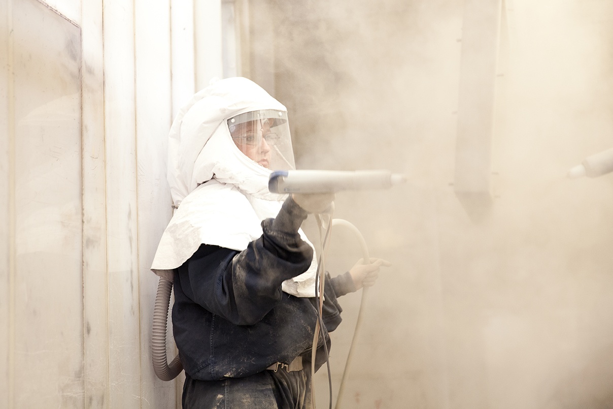 worker spraying coating on custom medical cart