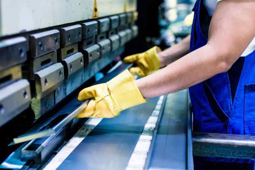 a person with gloved hands handling manufacturing equipment