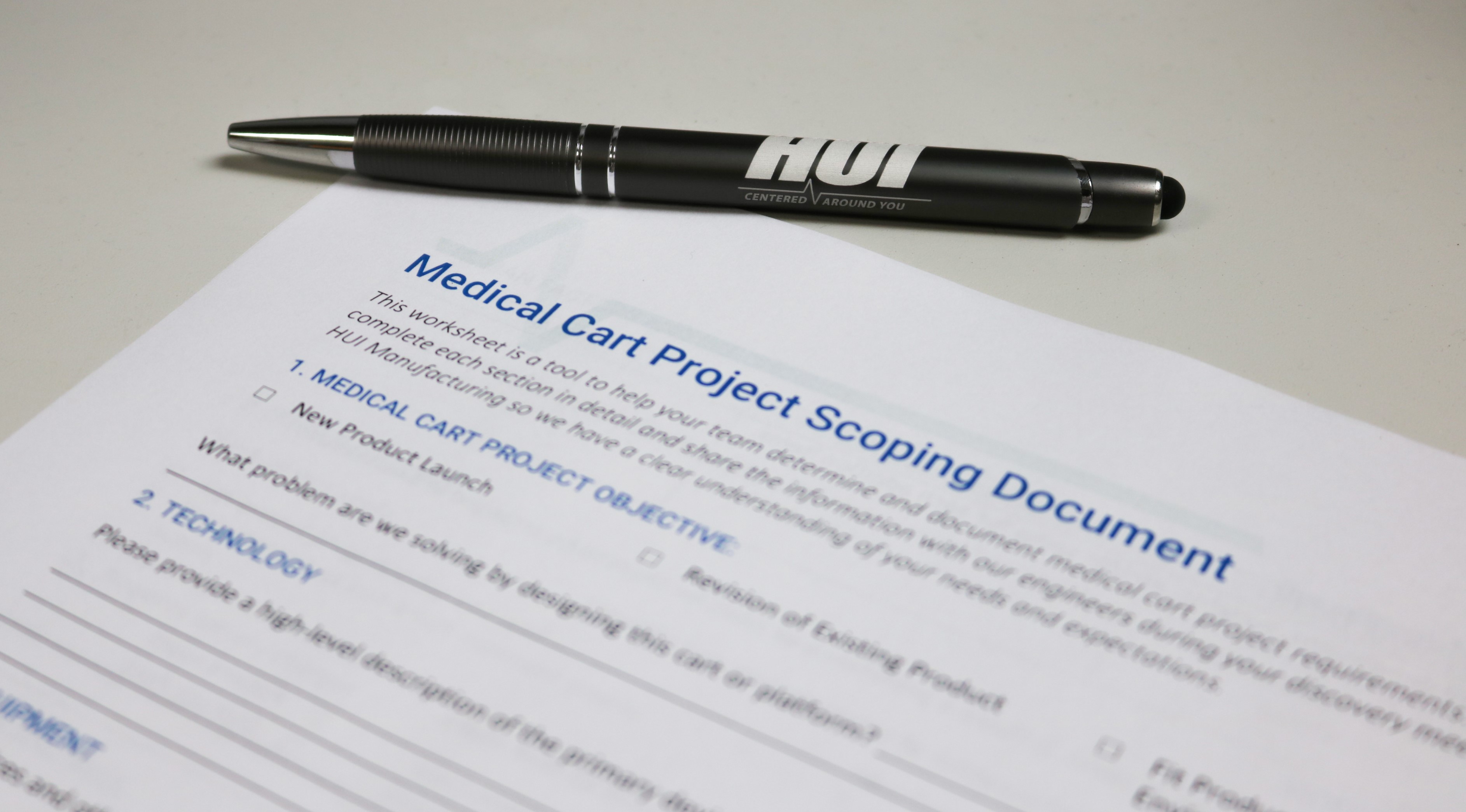 paper titled medical cart project scoping document on desk with pen