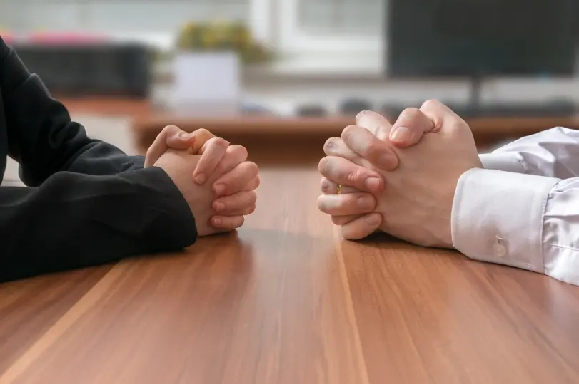 two people each with their hands clasped on top of a table