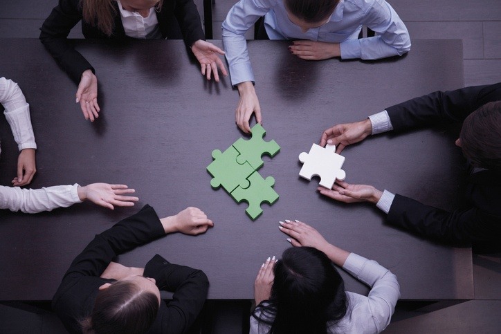 people sitting at a table putting together large puzzle pieces