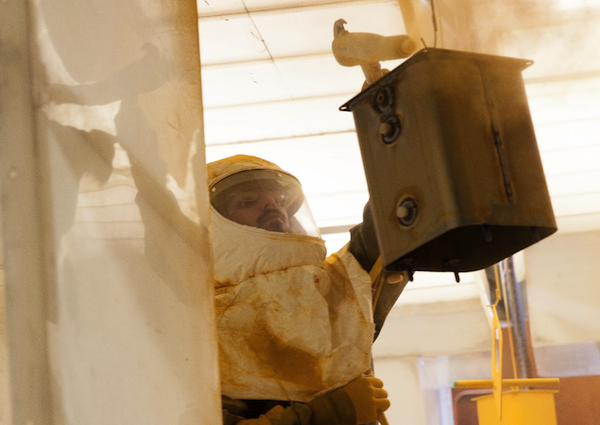 man dressed in proper protective equipment while applying powder coat